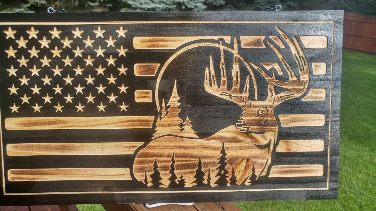 Wooden flag with deer and trees carving.