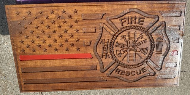 Wooden plaque with firefighter emblem and flag.